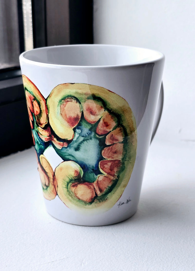 A ceramic mug with a colorful artistic depiction of a kidney on it, placed on a surface with a window in the background. Perfect doctor or urologist gift.