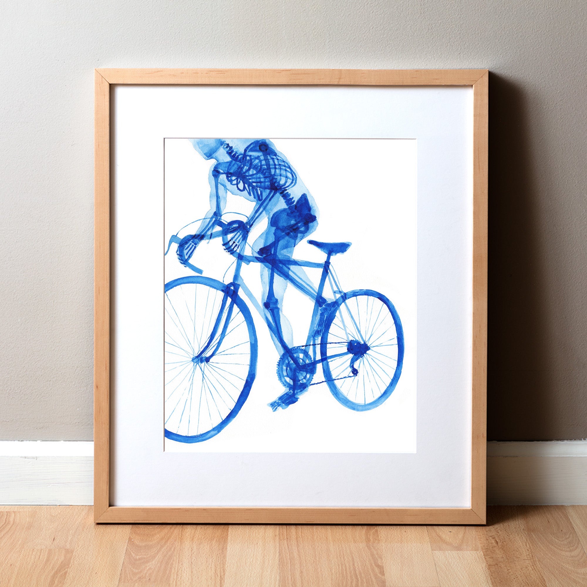 A framed watercolor print depicting the skeletal anatomy of a biker riding a bicycle, with a blue color scheme on a white background. Perfect as a PT gift or for cyclist or biker art.