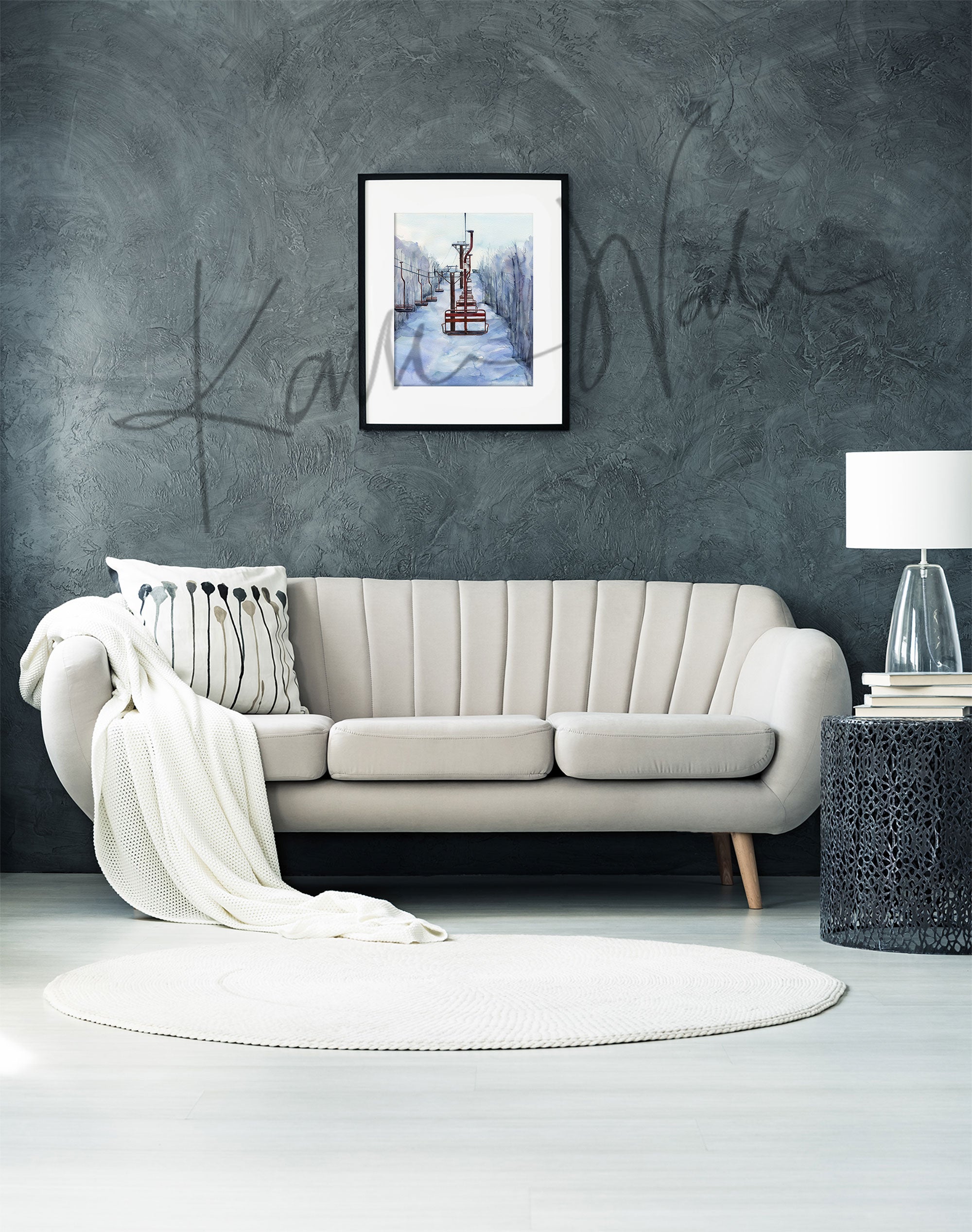 Framed watercolor painting of chairlifts in a snowy scene. The painting is hanging over a white couch.