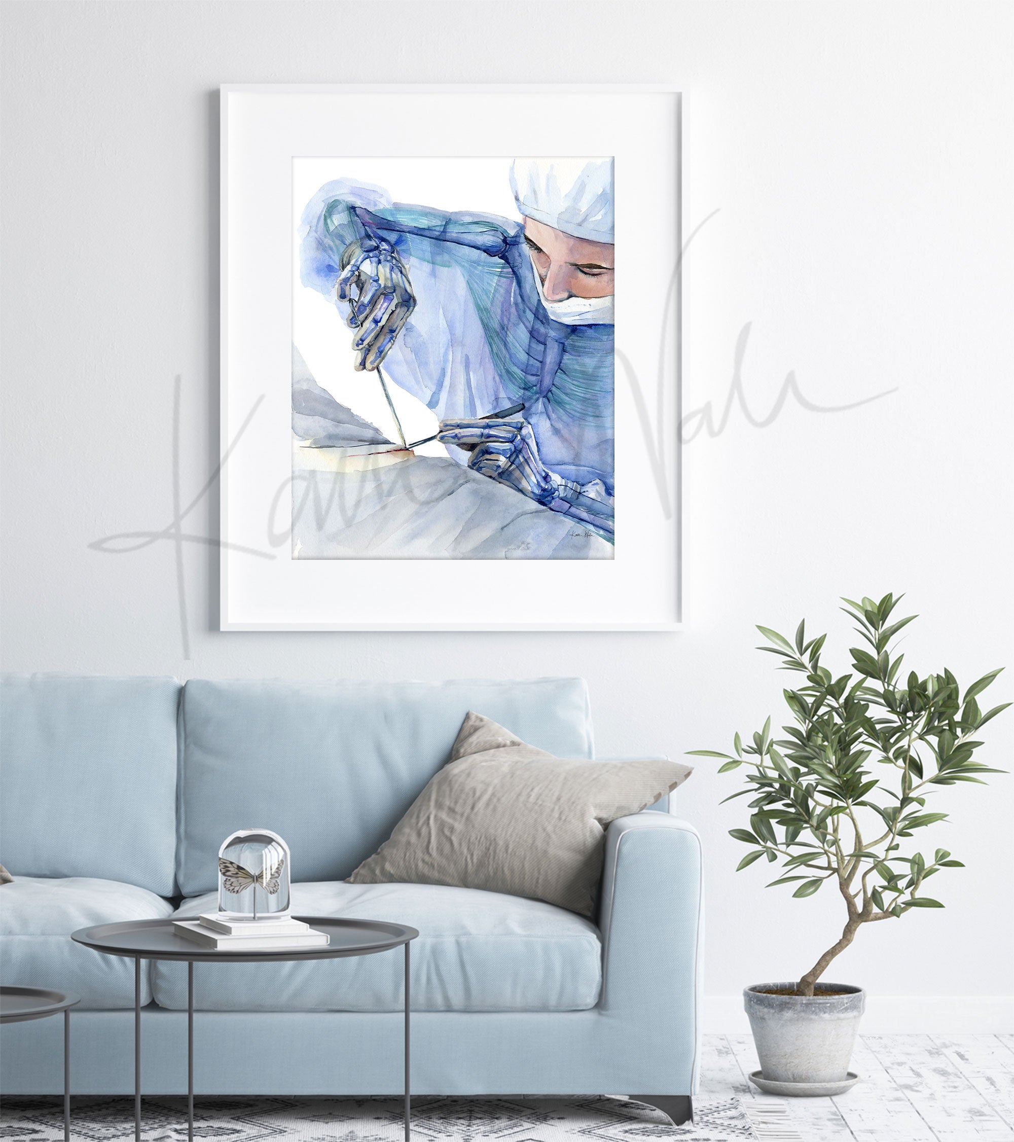Framed watercolor painting showing the ergonomics of a surgeon at work. The painting is hanging over a blue couch.