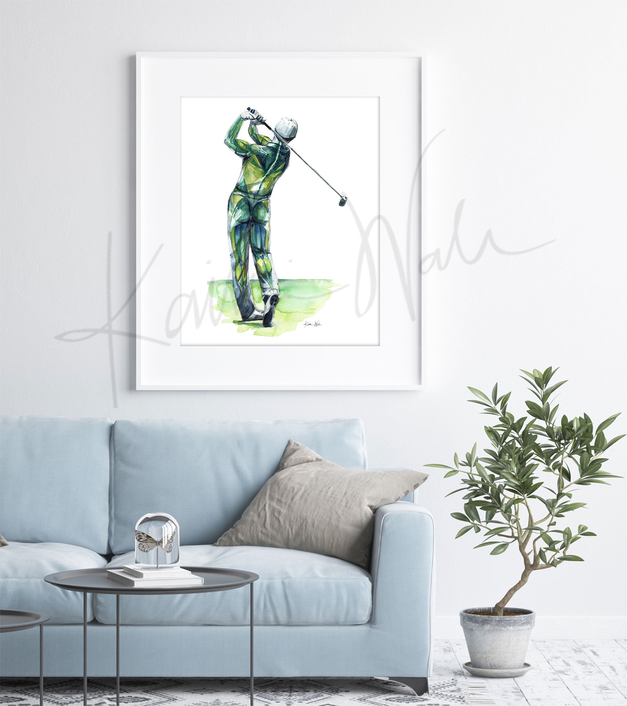 Framed watercolor painting of a golfer’s anatomy during a golf swing. The painting is hanging over a blue couch.