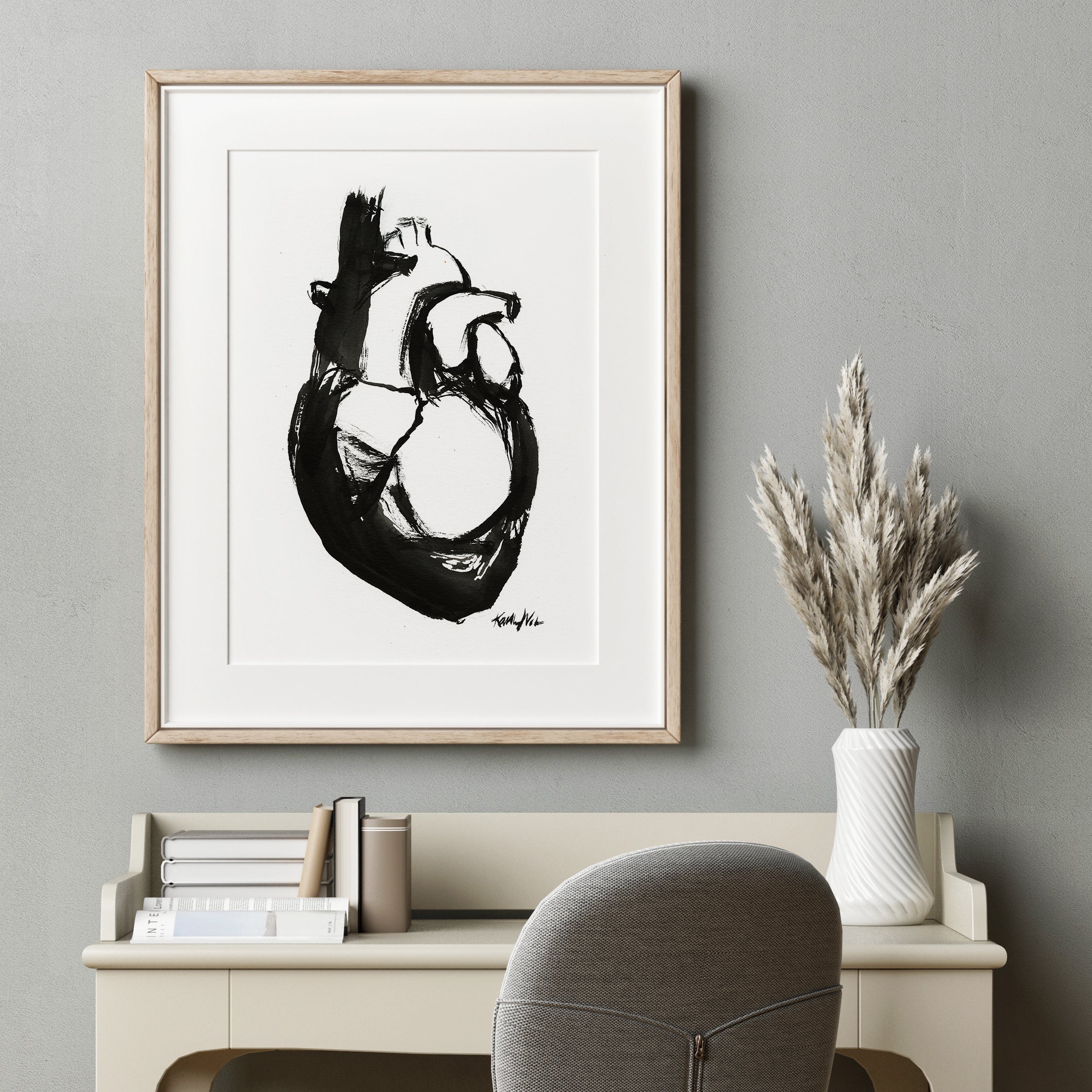 Framed black and white artwork of a heart anatomy art painting on a gray wall above a desk. Doctor's office art