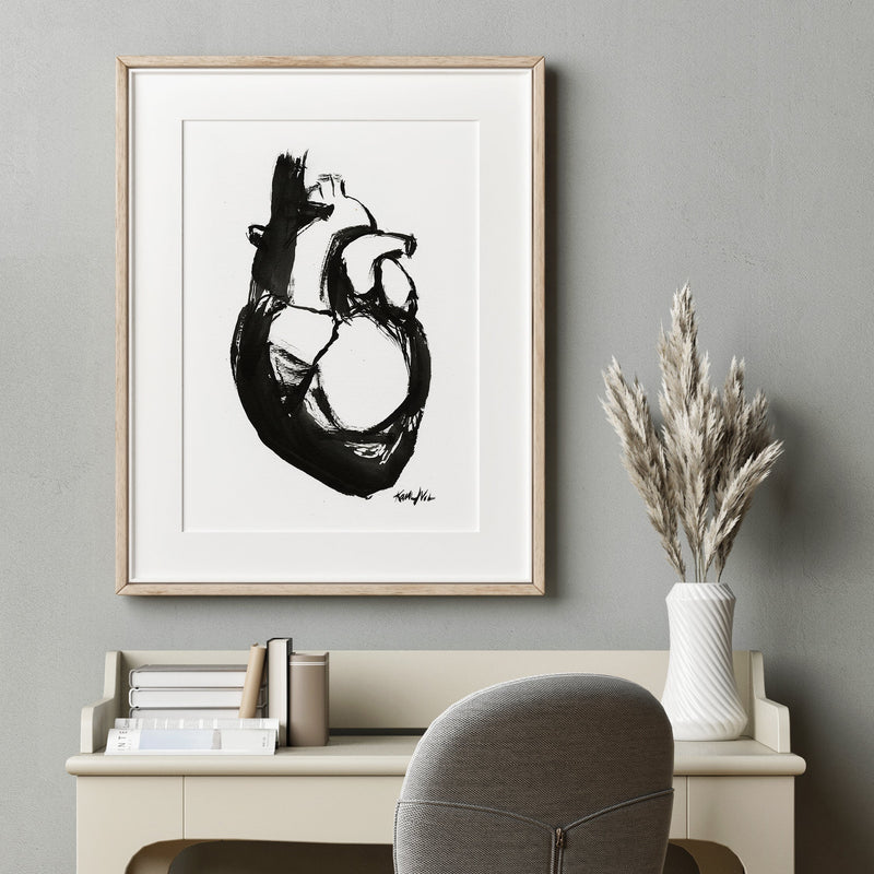 Framed black and white artwork of a heart anatomy art painting on a gray wall above a desk. Doctor's office art