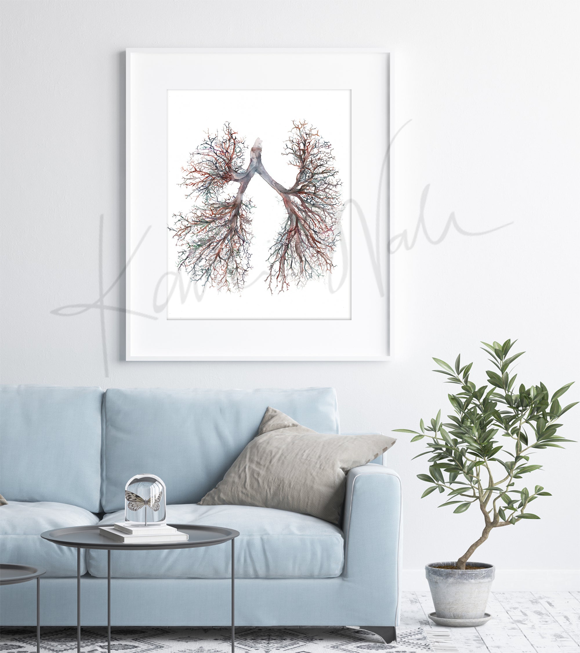 Doctor office decorating ideas. Framed artwork of watercolor lungs on a wall above a light blue sofa with a plant and coffee table in a doctor's office.