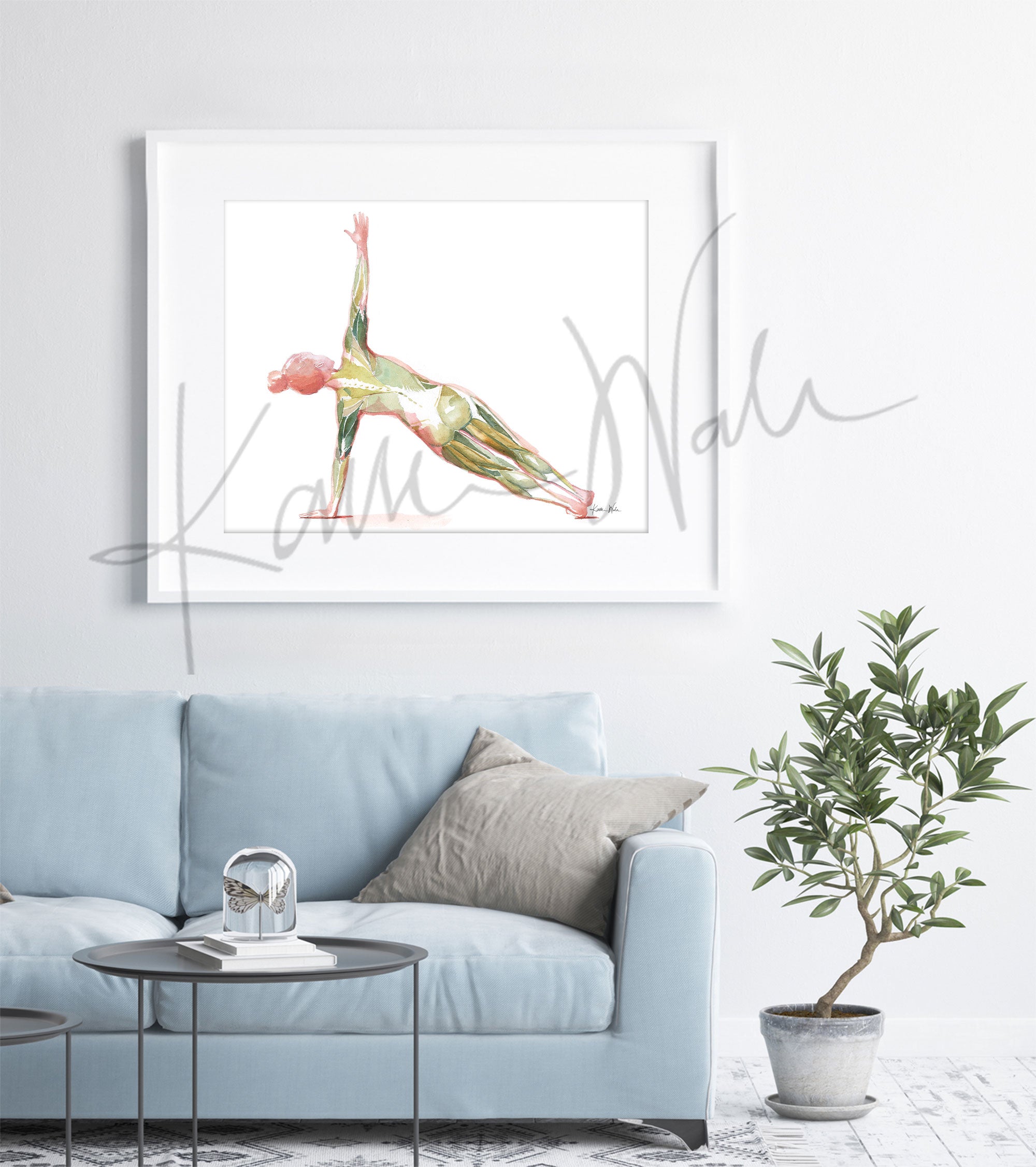 Framed watercolor painting of a woman performing the side plank yoga pose. The image shows her muscular anatomy while doing the pose. The painting is hanging over a blue couch.