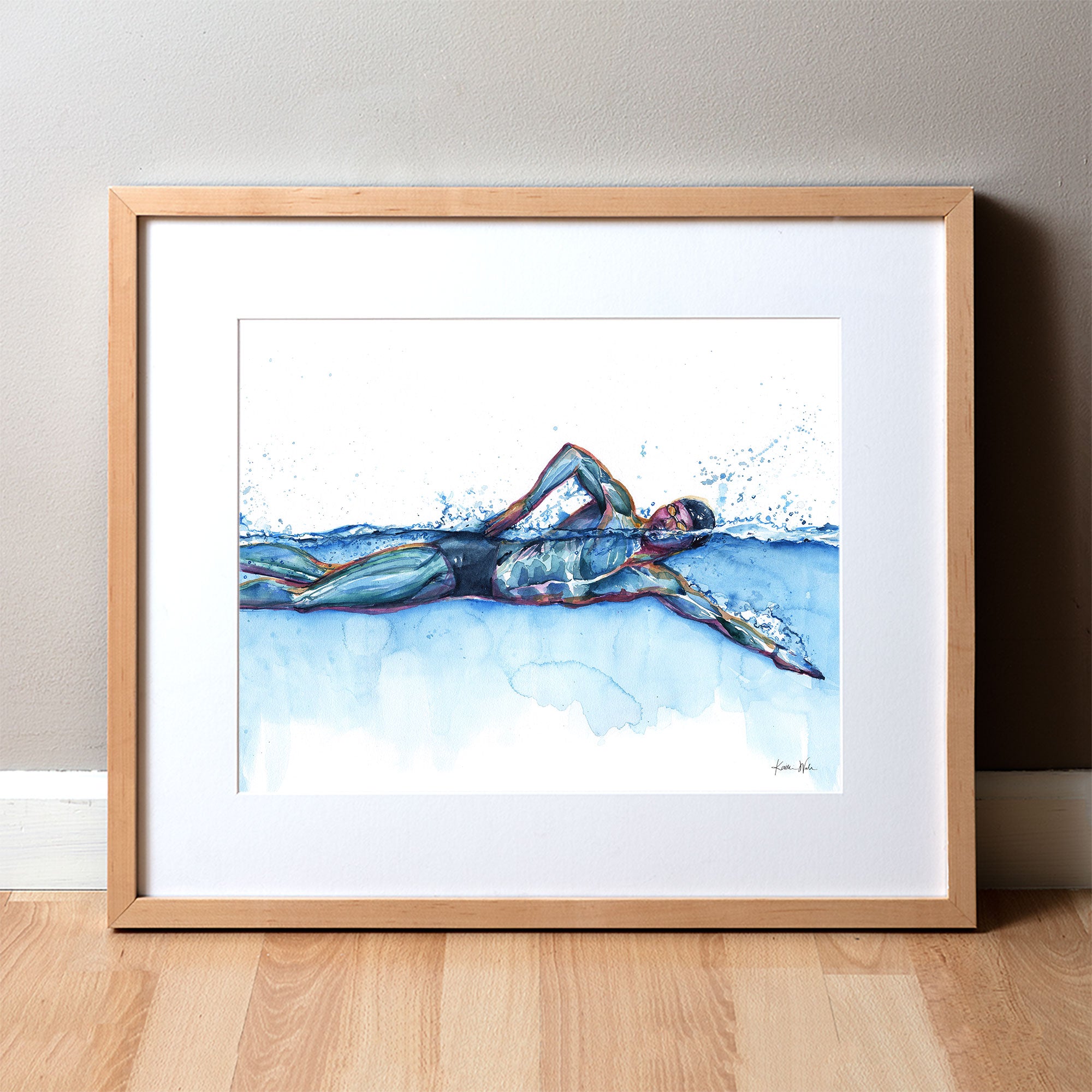 Framed watercolor painting of a swimmer in mid stroke showing the swimmer’s muscular anatomy.