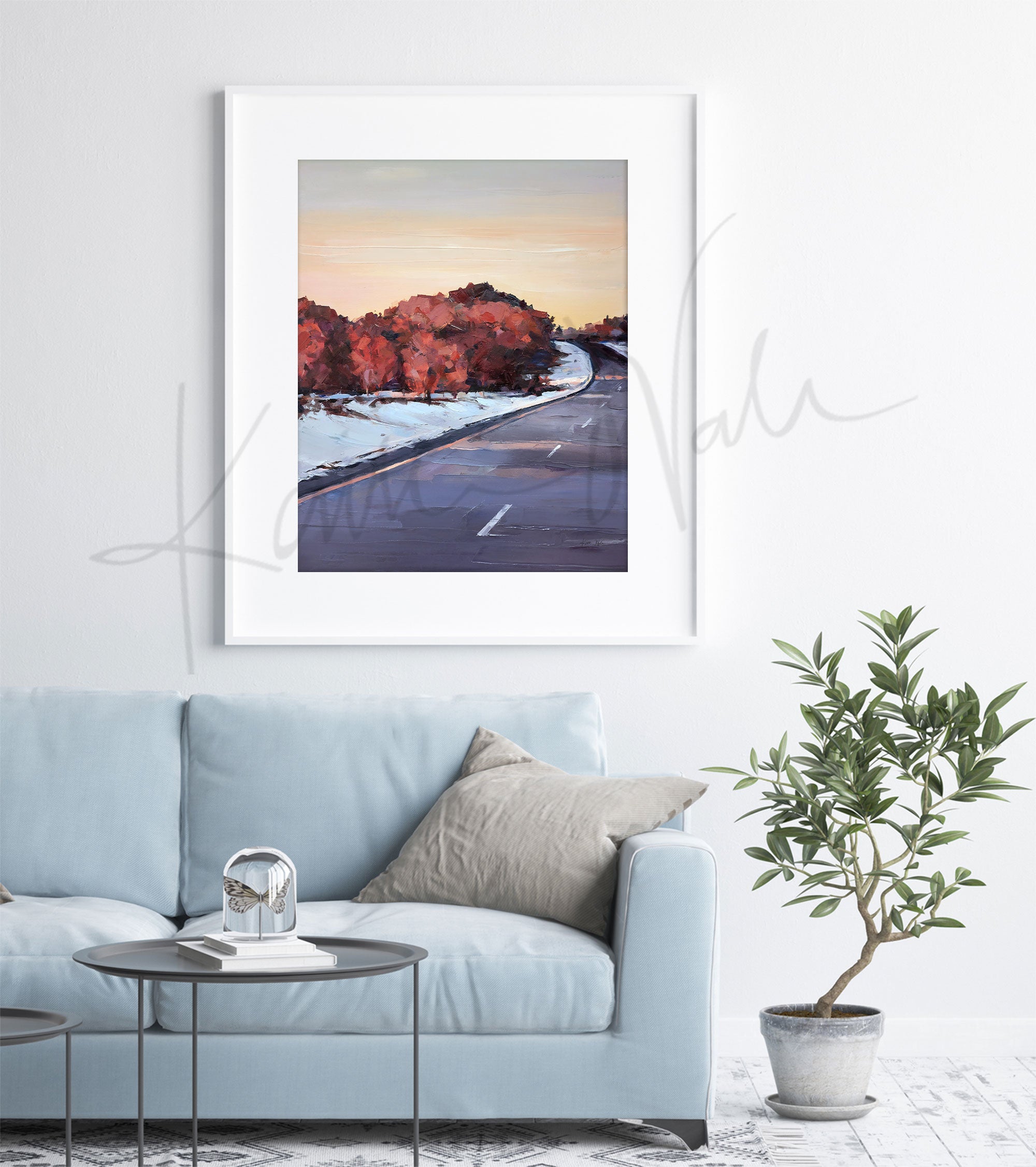 Framed watercolor painting of a snowy Wisconsin landscape in the spring. The painting is hanging over a blue couch.