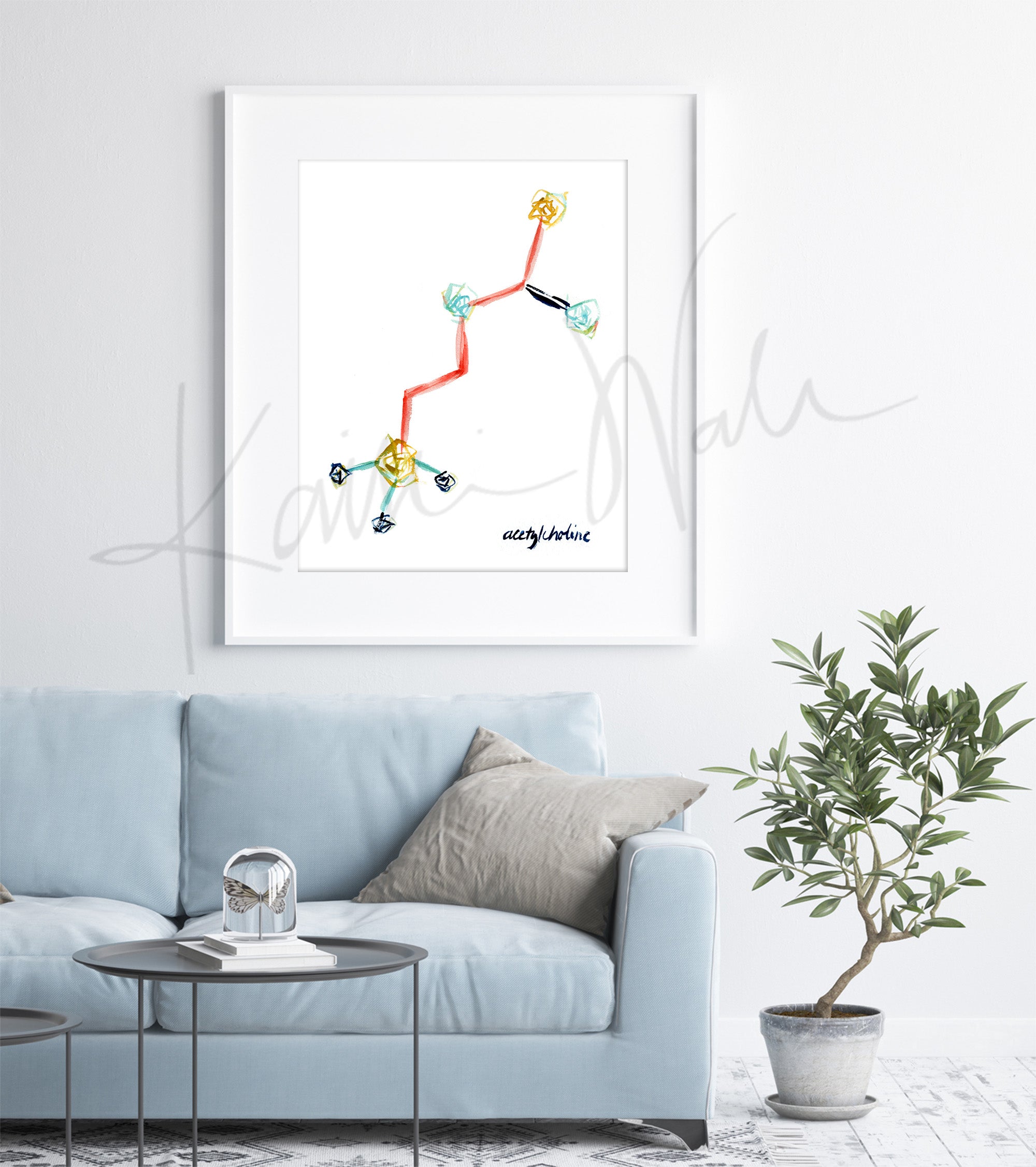 Framed watercolor painting of the acetylcholine structure in blues, yellow and reds. The painting is hanging over a blue couch.