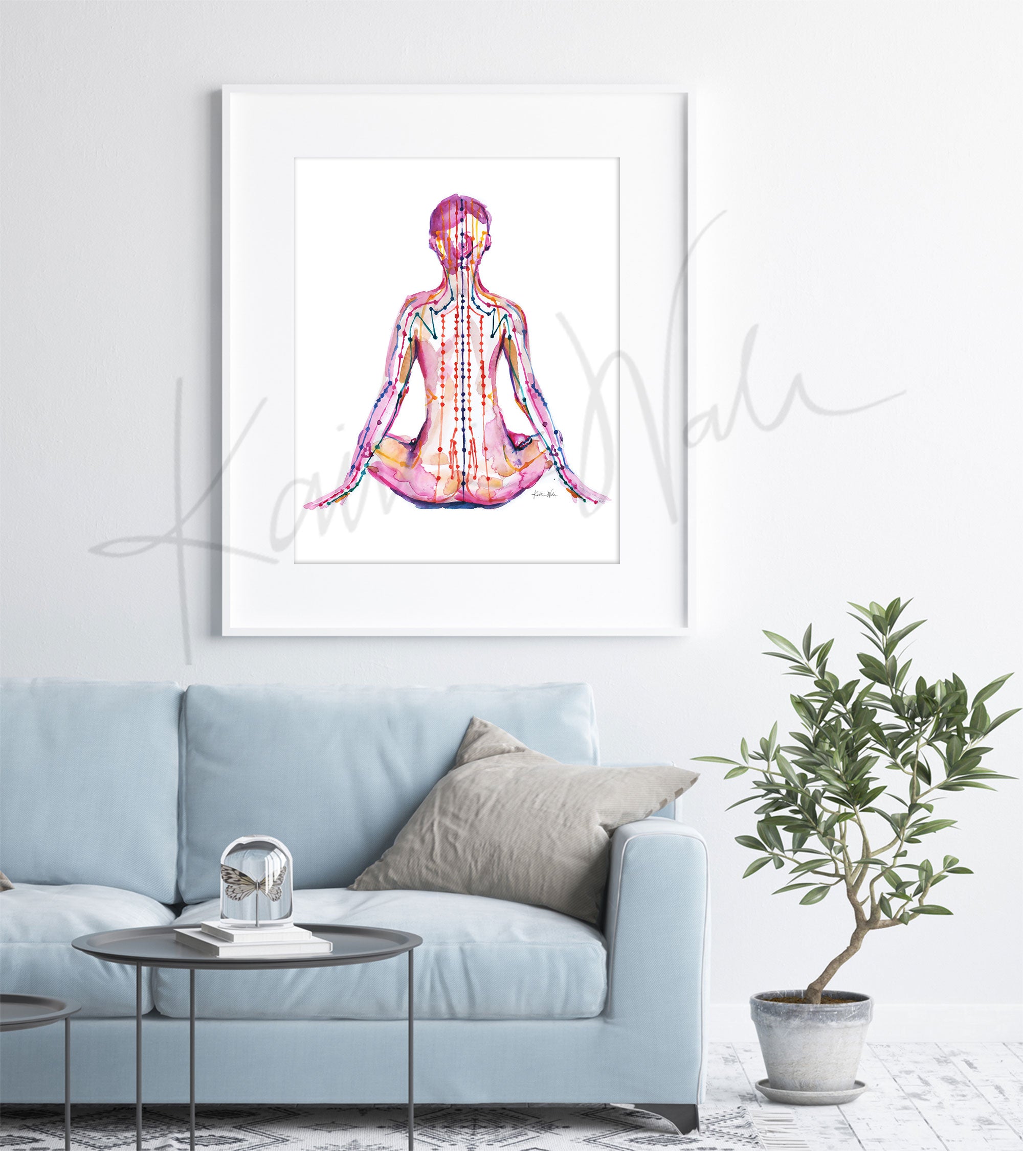 Framed watercolor painting of a person sitting in a meditative pose with meridian paths showing. The painting is hanging over a blue couch.