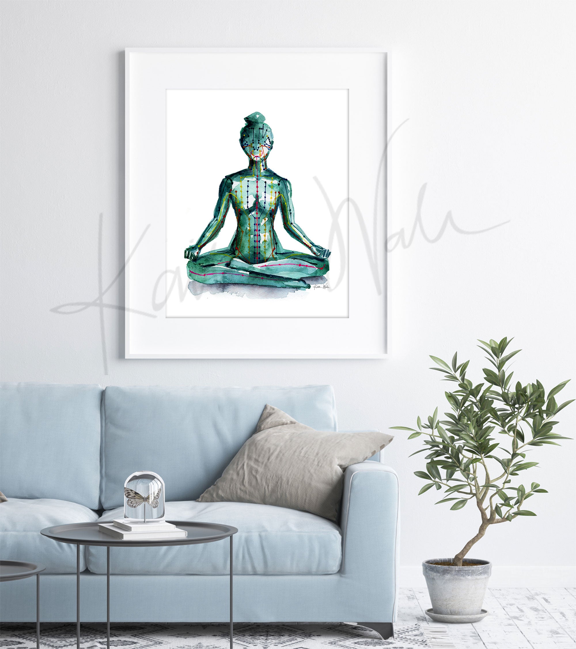 Framed watercolor painting of a person sitting in a meditative pose with meridian paths showing. The painting is hanging over a blue couch.