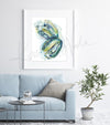 Framed watercolor painting of a heart dissection in greens blues and yellows.. The painting is hanging over a blue couch.
