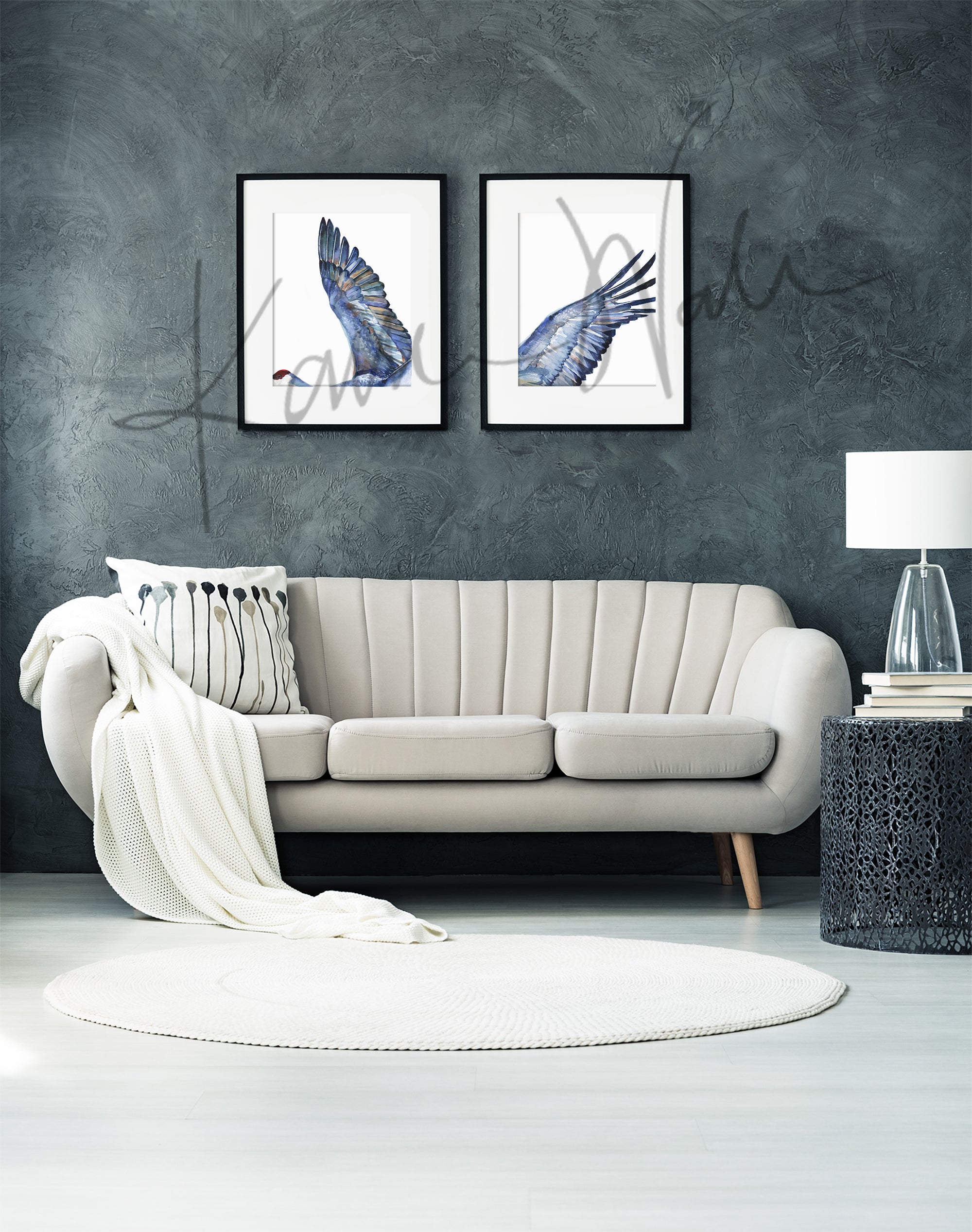  Framed watercolor diptych of a crane's wings. The paintings are hanging over a white couch.