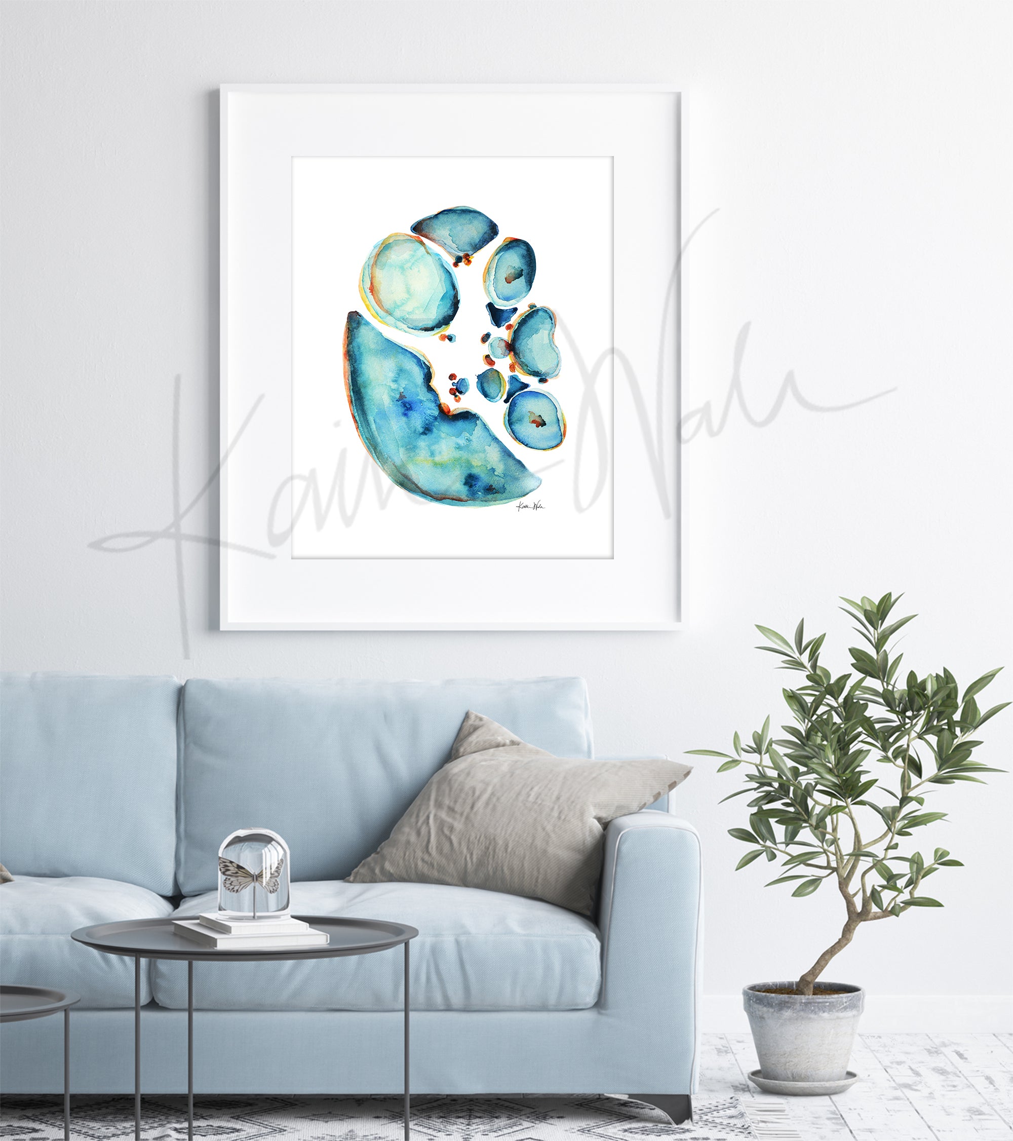 Framed watercolor painting showing a cross section of an abdomen in blues and teals with pops of orange and yellow. The painting hangs above a blue couch.