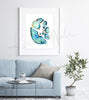 Framed watercolor painting showing a cross section of an abdomen in blues and teals with pops of orange and yellow. The painting hangs above a blue couch.