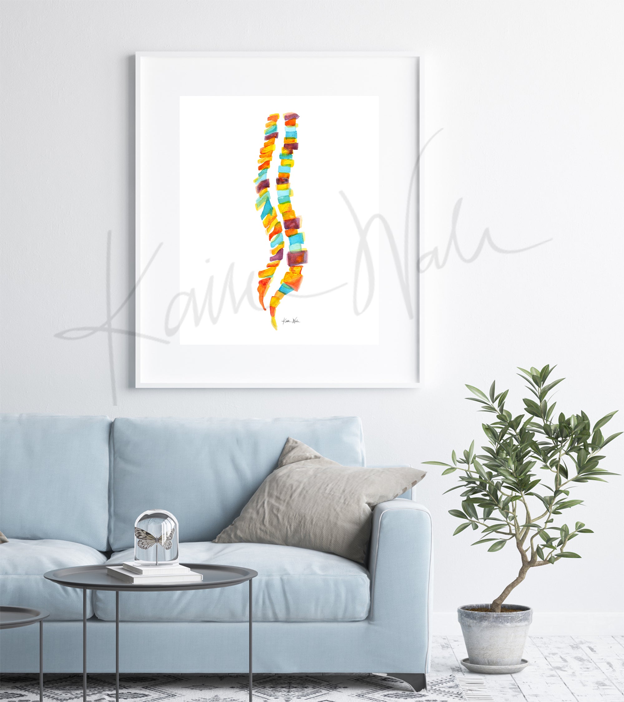 Framed watercolor painting of a spinal columns in yellow, orange, burgundy and teal. The painting hangs over a blue couch.
