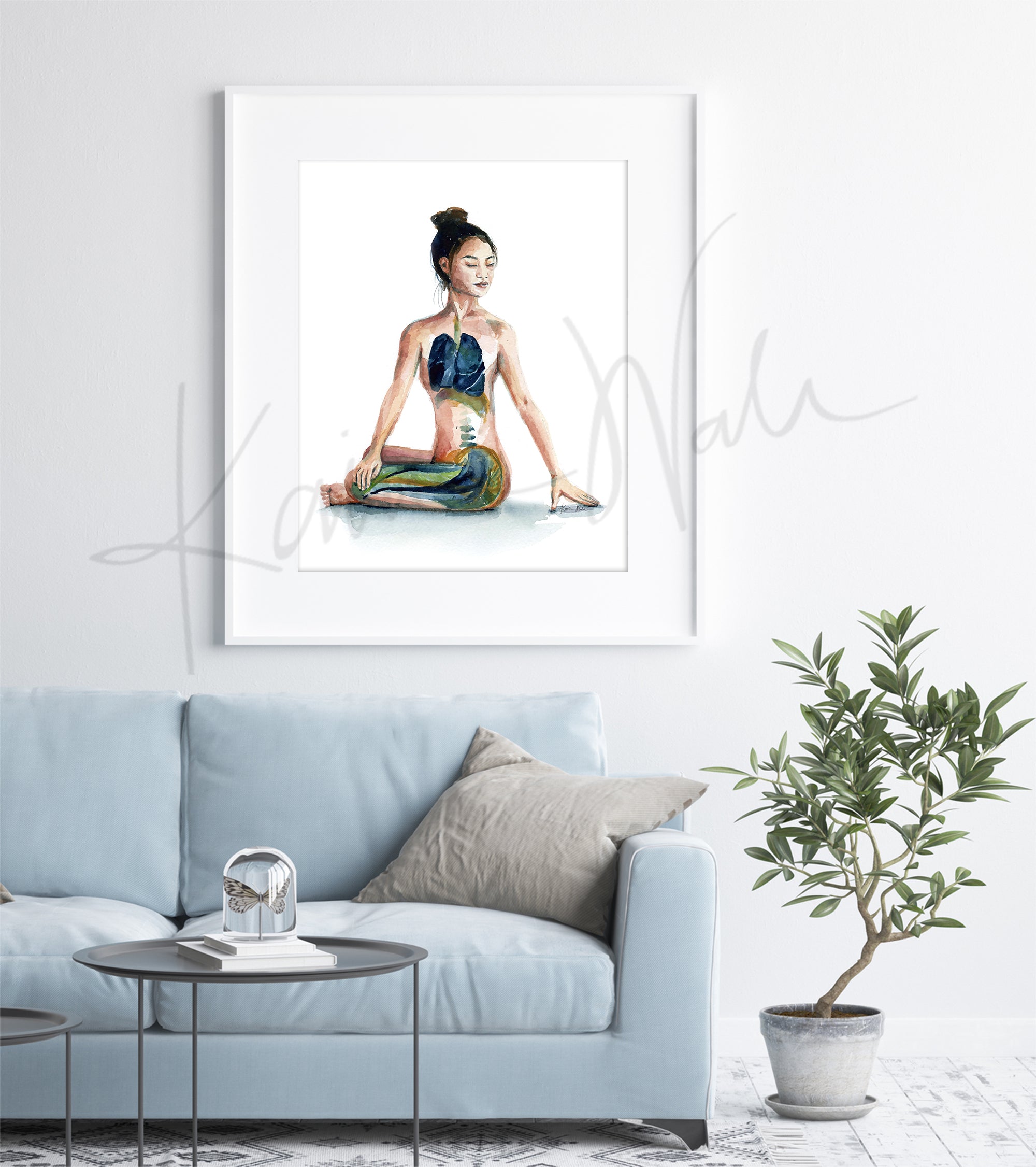 Framed watercolor painting of a woman with her eyes closed in a seated yoga pose. The painting is hanging over a blue couch.