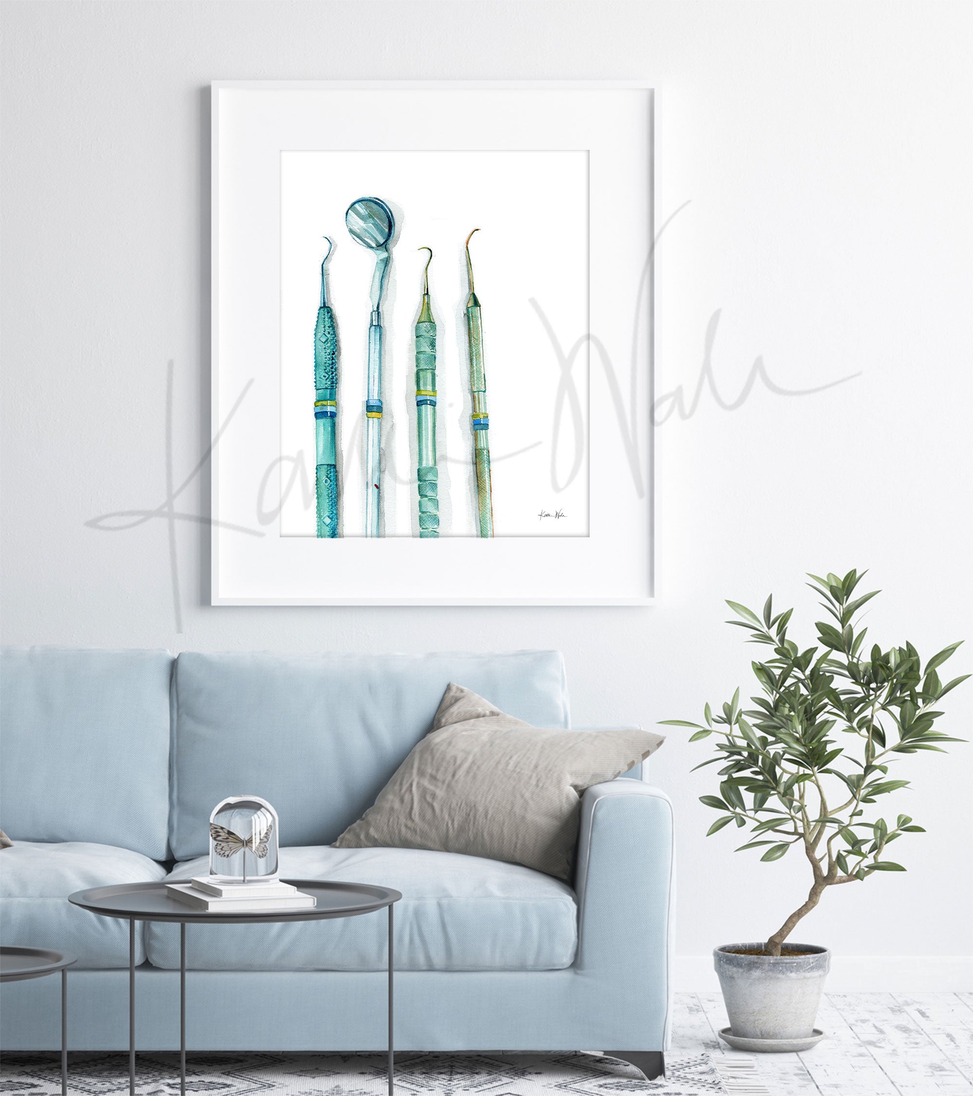 Framed watercolor print of dental hygienist tools. The painting is hanging over a blue couch.