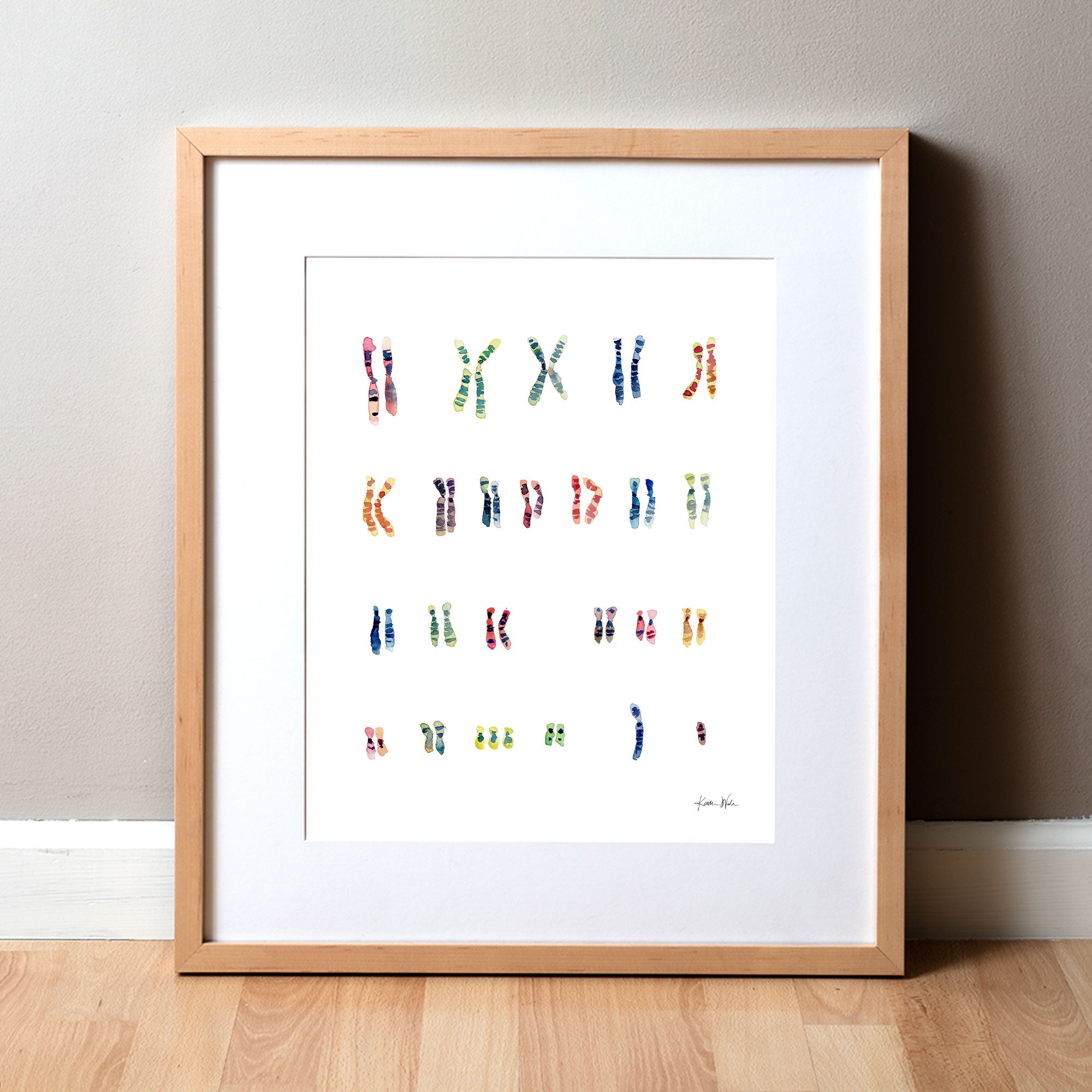 Framed watercolor painting of the karyotype of someone with Down Syndrome.