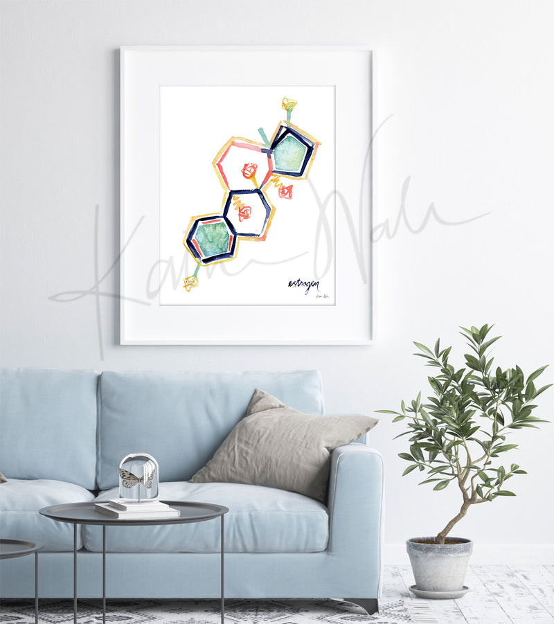 Framed watercolor painting of the estrogen hormone structure. The painting is hanging over a blue couch.