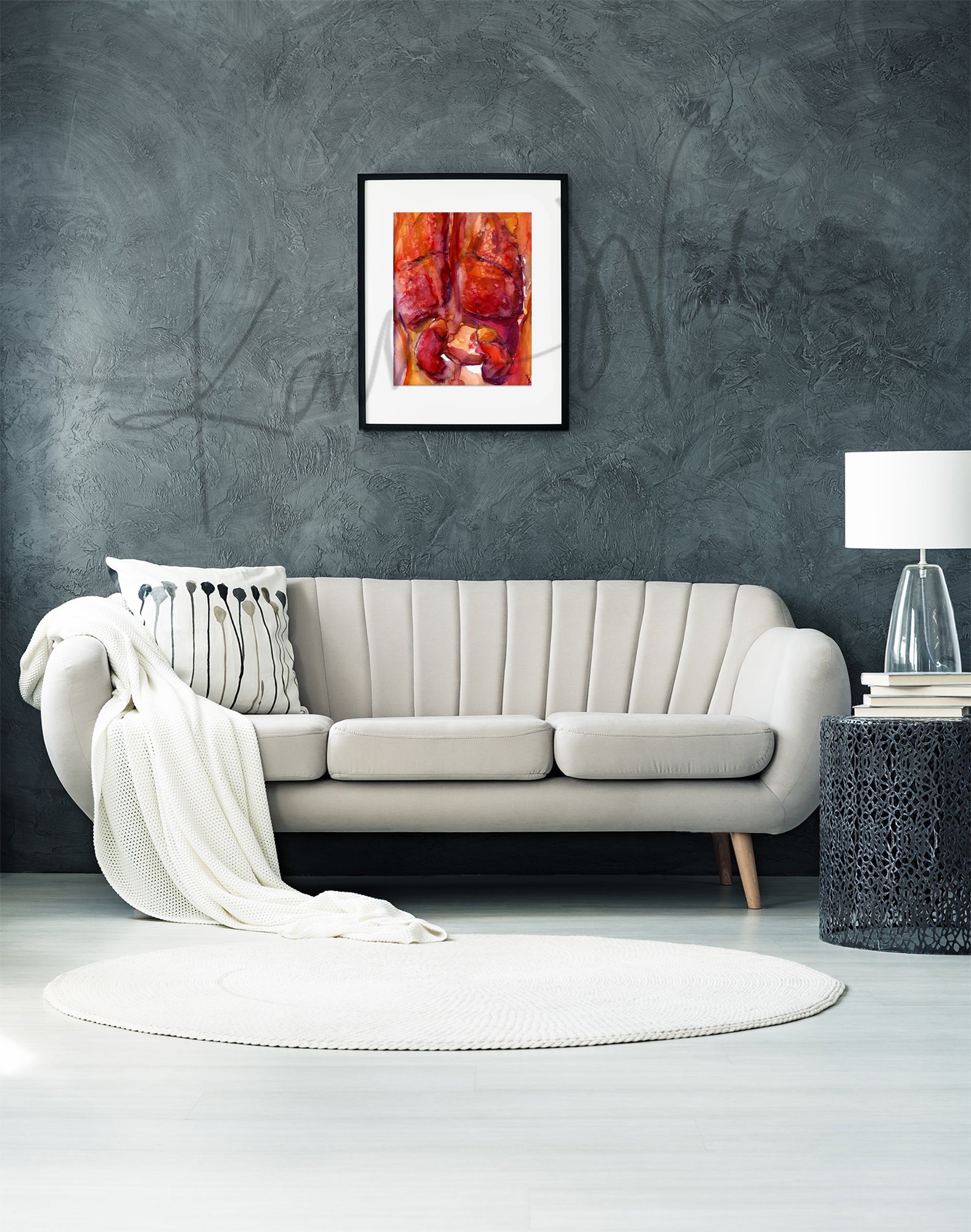 Framed watercolor painting of the internal trunk organs in reds and oranges.. The painting is hanging over a white couch. 