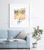 Framed watercolor painting of the gastrointestinal and urinary system. The painting is hanging over a blue couch.