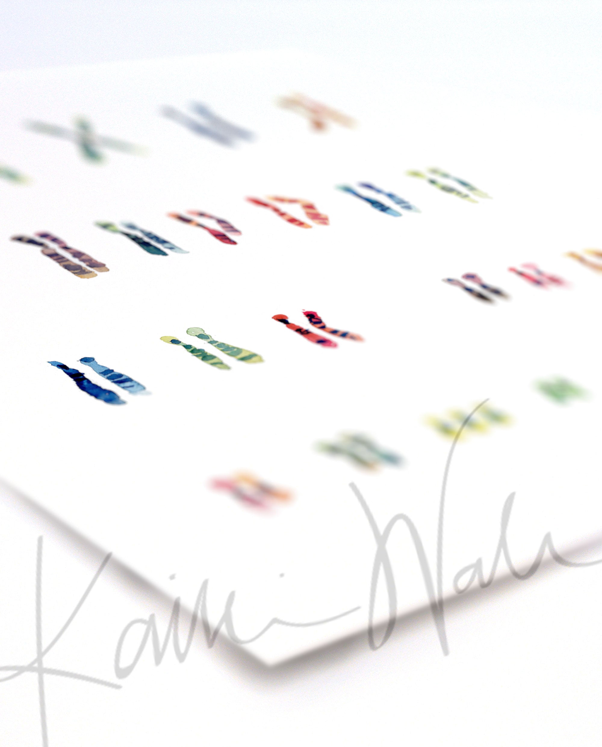 Angled view of a watercolor painting of the karyotype of someone with Down Syndrome.
