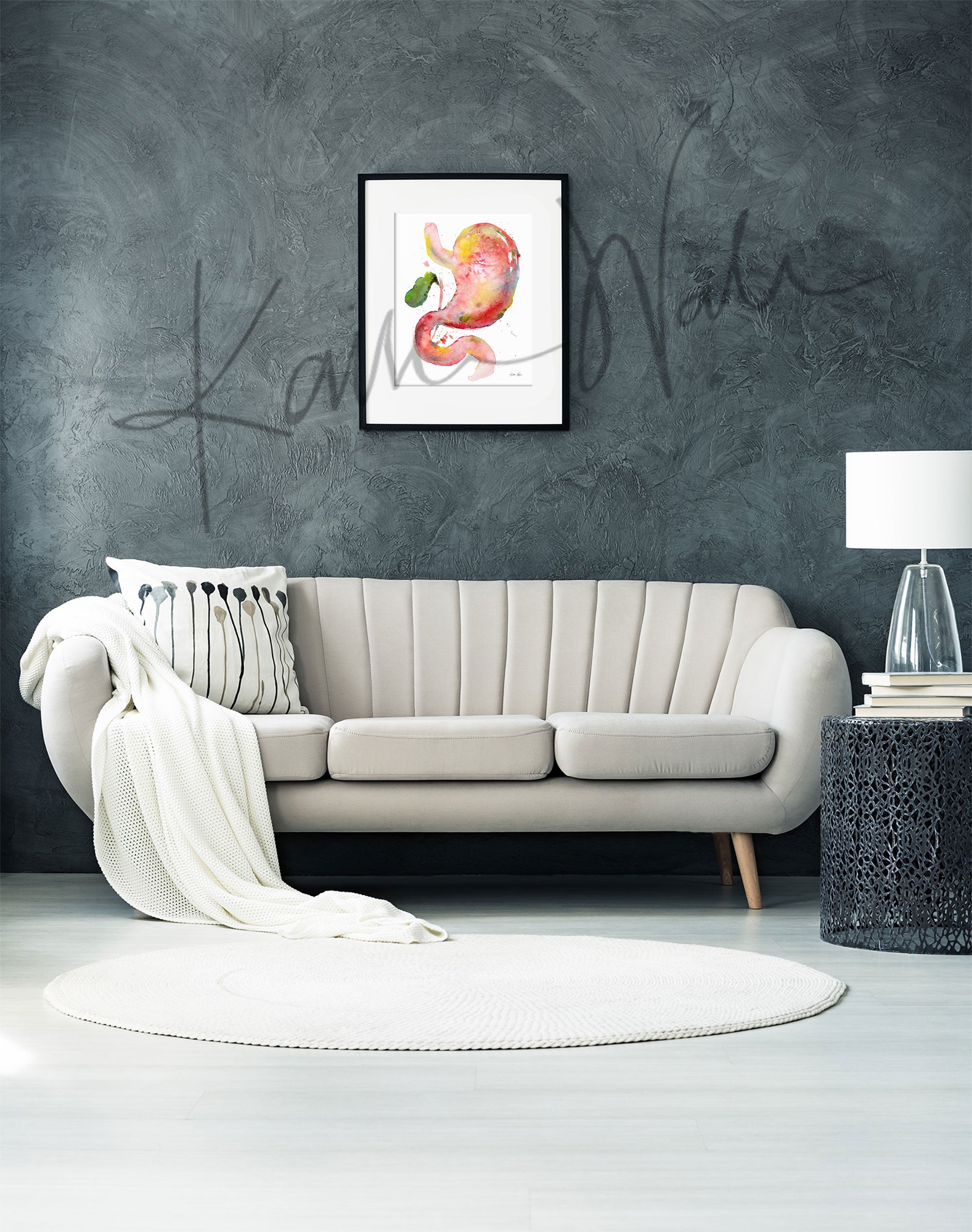 Framed watercolor painting of a stomach, duodenum, and gallbladder combination. The painting is hanging over a white couch.