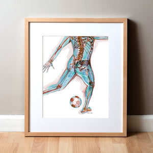 Framed watercolor painting of a soccer player kicking a ball. Painting shows a soccer player at a muscular and skeletal level.