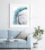 Framed watercolor painting of a zoomed in perspective of a white guinea pig’s nose on a teal, blue, and green background. The painting is hanging over a blue couch.