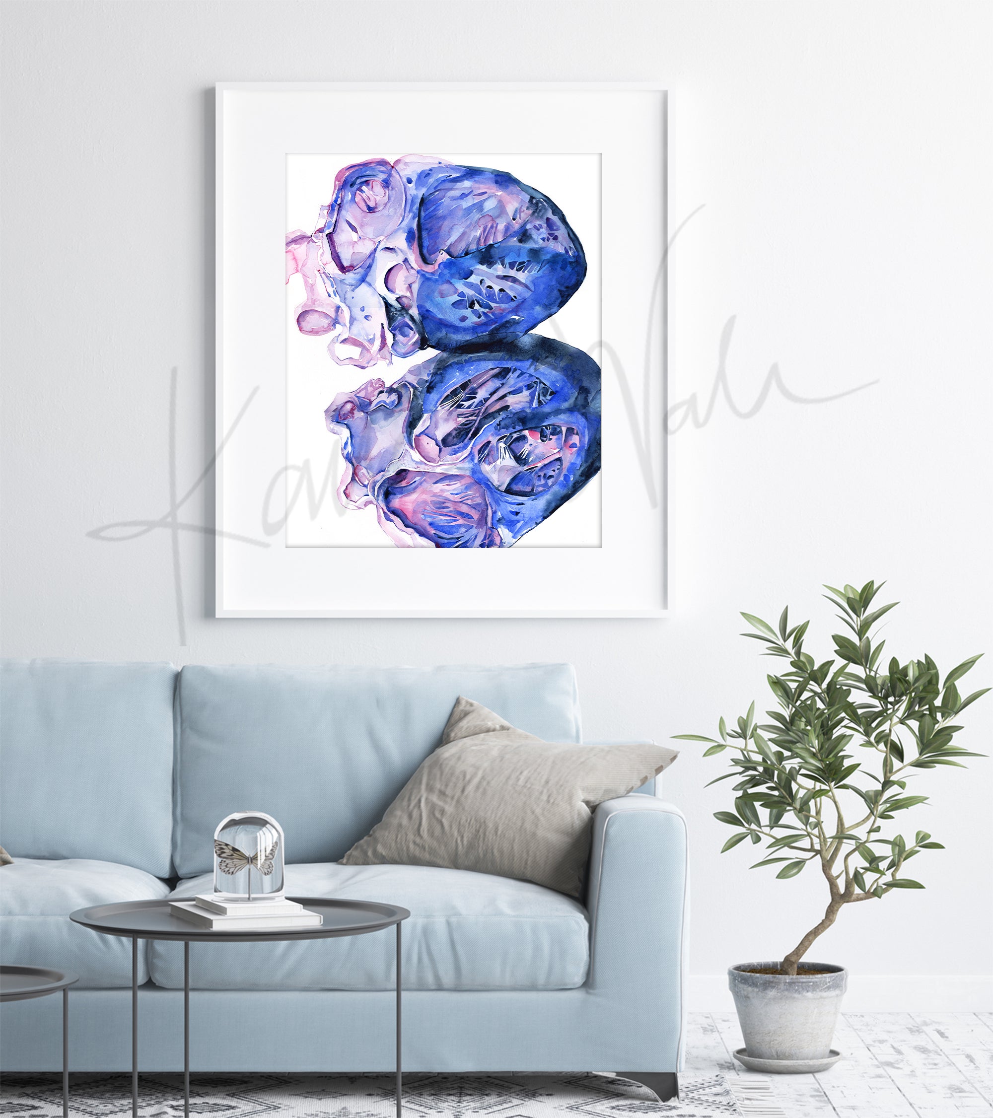 Framed watercolor painting of a heart dissection in pinks, purples, and vibrant blues. The painting is hanging over a blue couch.