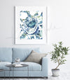 Framed watercolor painting of a granuloma histology in blues and greens.. The painting is hanging over a blue couch.