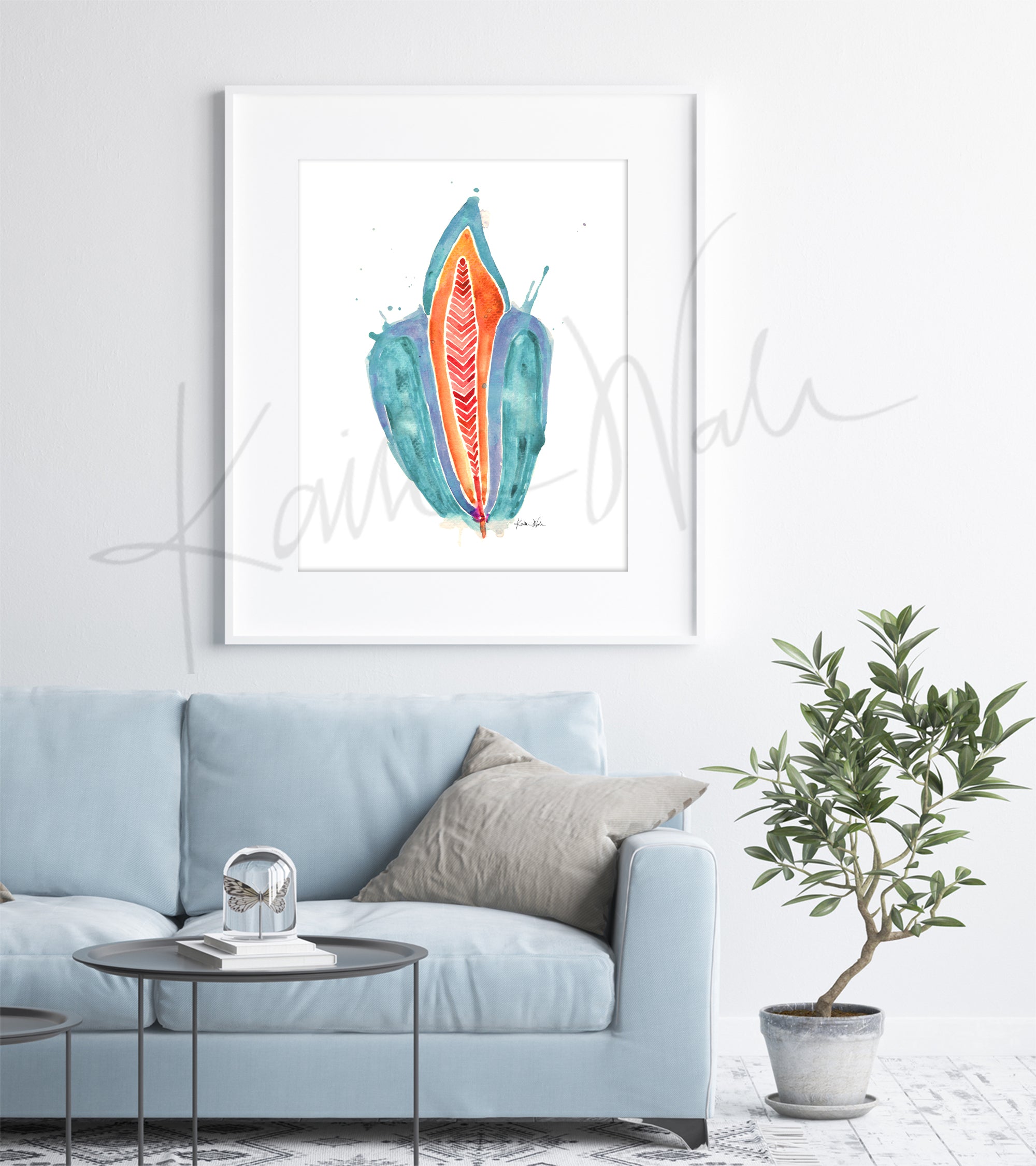 Framed watercolor painting of an abstract incisor in teal, orange, and red. The painting hangs above a blue couch.
