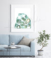 Framed watercolor painting of an ovulation cycle. The painting is hanging over a blue couch.
