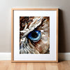 Framed watercolor painting of a zoomed in perspective of an owl eye. The iris is blue and feathers around the eye are painted in tans and browns.