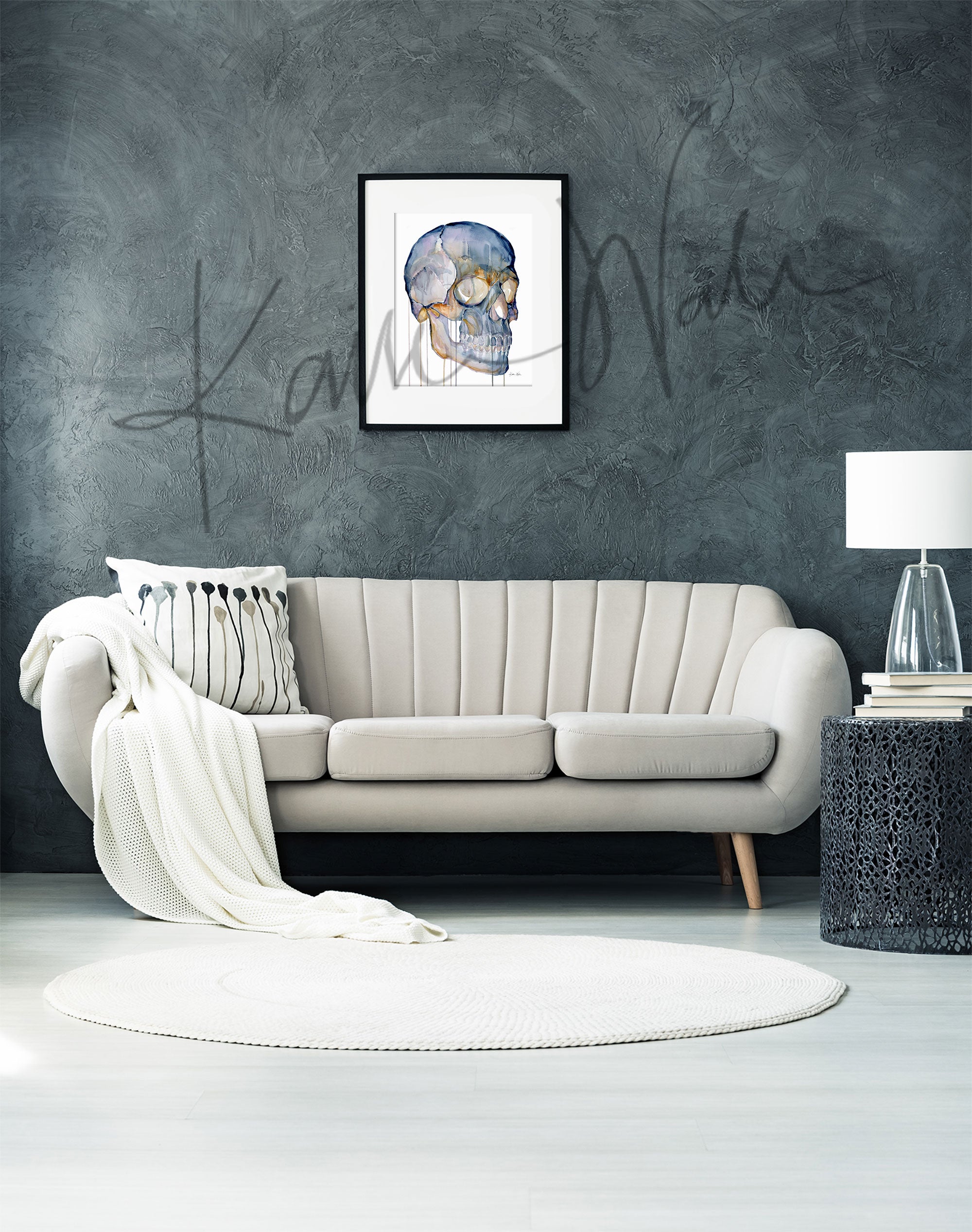 Framed watercolor painting of a skull from a three quarter view. The painting is hanging over a white couch.