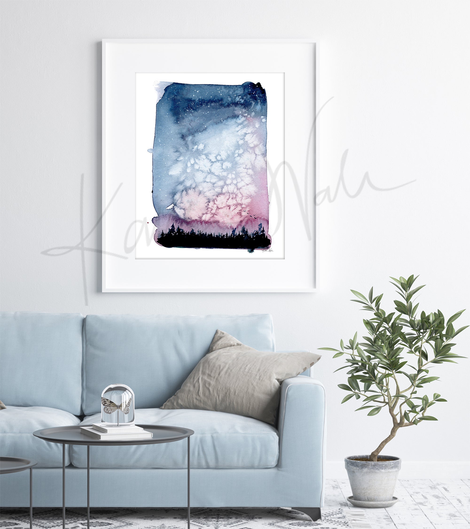 Framed watercolor painting of a beautiful night sky with silhouetted trees. The painting is hanging over a blue couch.