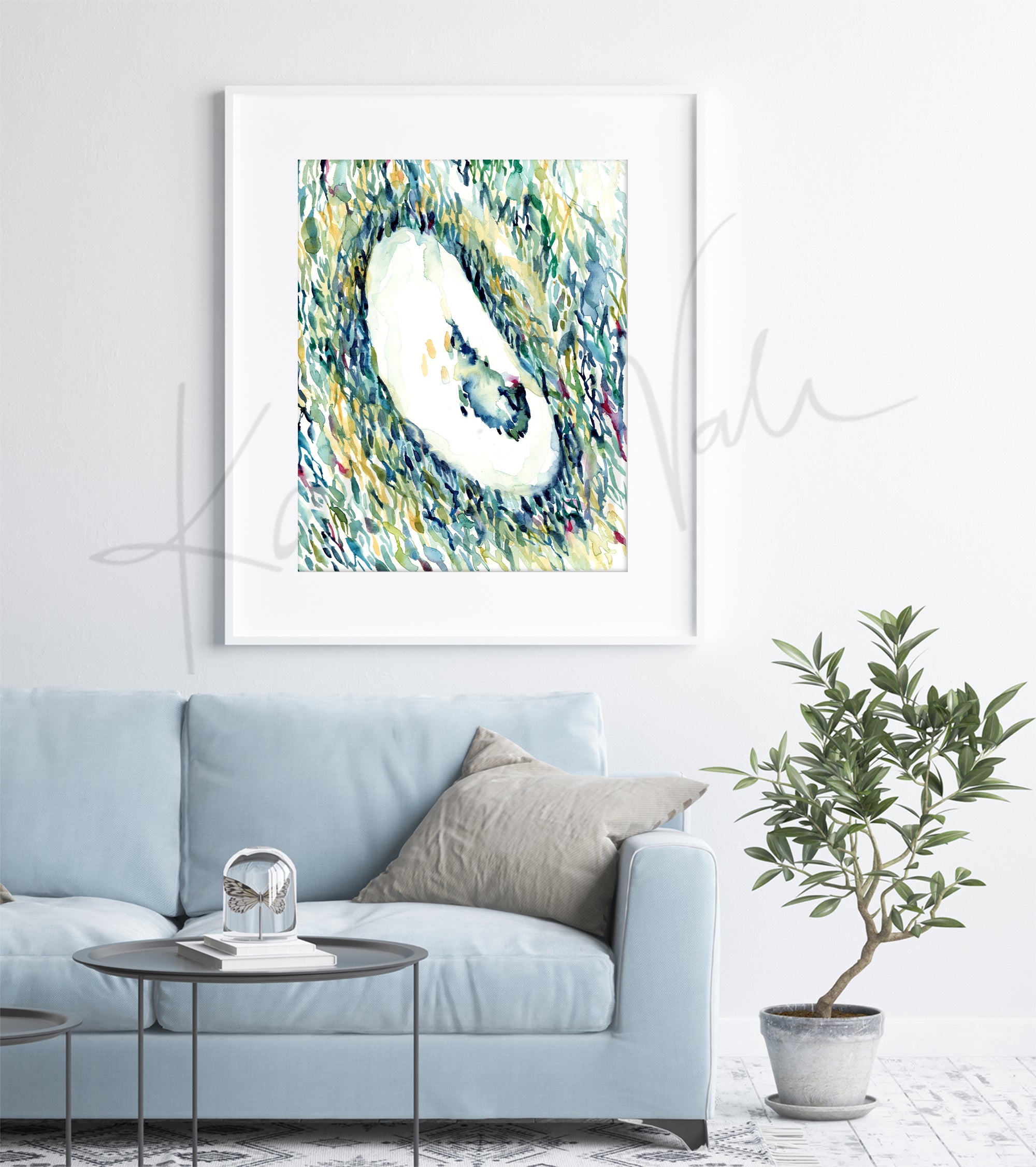 Framed watercolor painting of an IVF ultrasound. The painting is hanging over a blue couch.