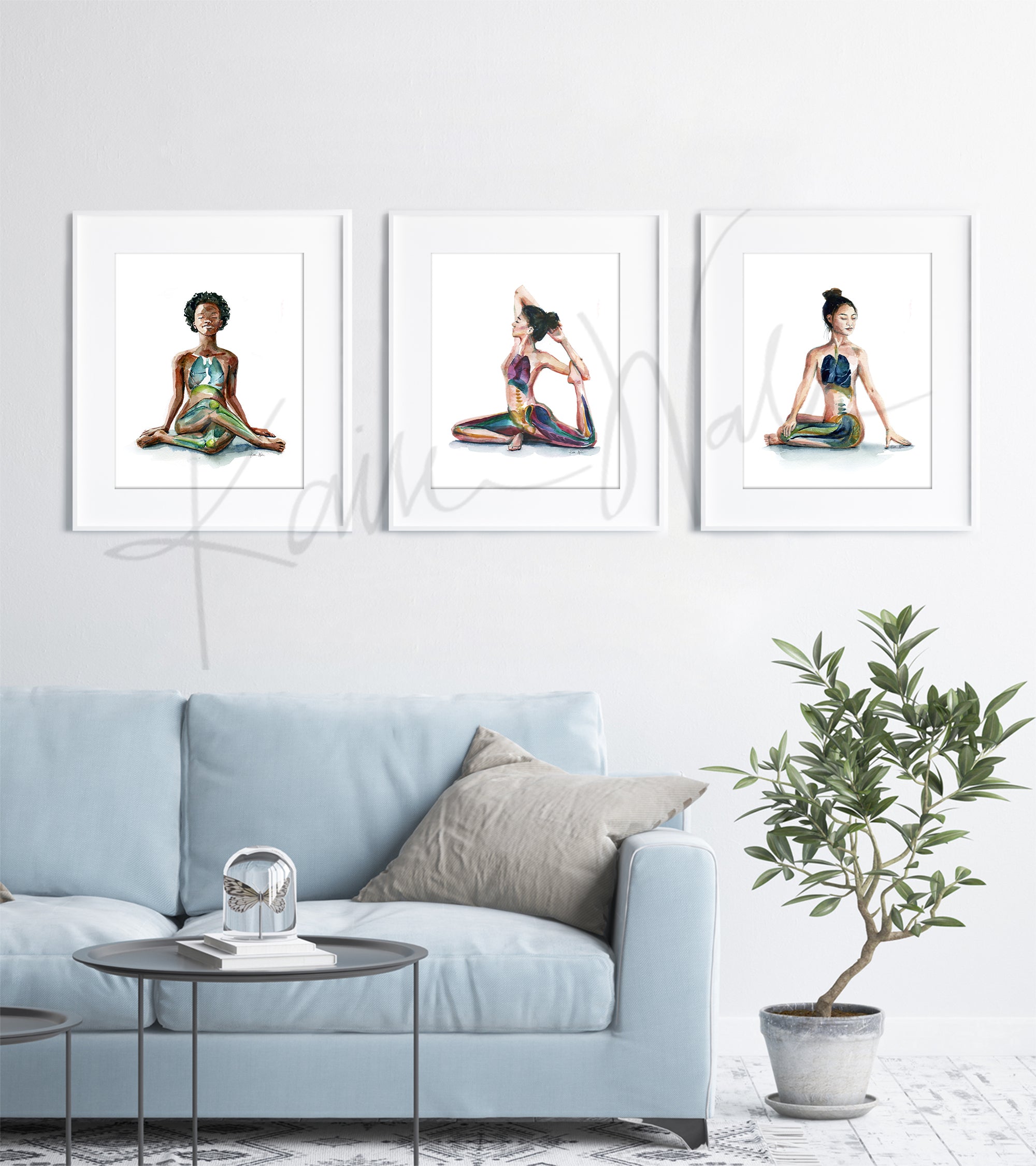 Framed watercolor painting set of 3 seated yoga poses. The painting is hanging over a blue couch. 